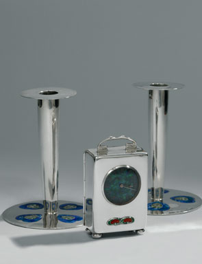 Sepasang tempat lilin dan jam meja yang didesain oleh Archibald Knox (Inggris, 1864-1933). 